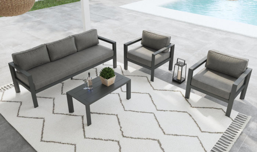 All-gray outdoor furniture group: loveseat, two chairs, coffee table, on rug with potted plant accents